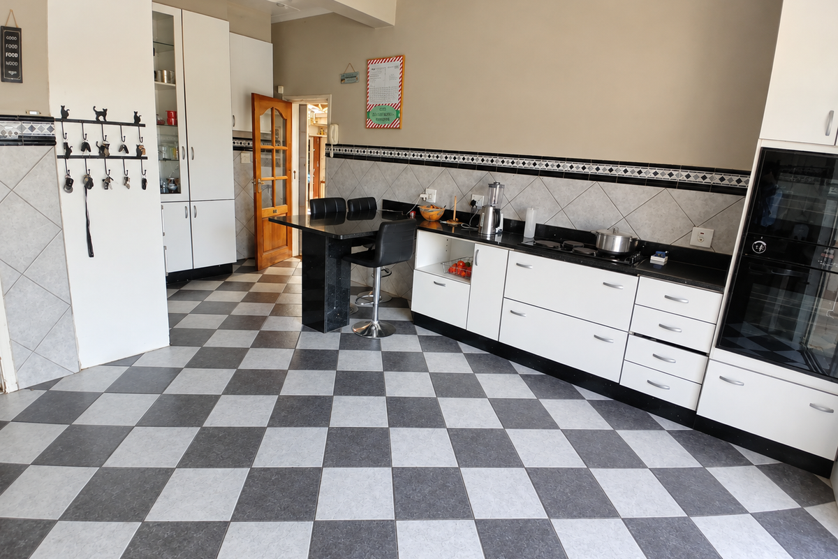 A functional kitchen featuring white cabinetry, black granite countertops, integrated oven, and a distinctive checkered tile floor.