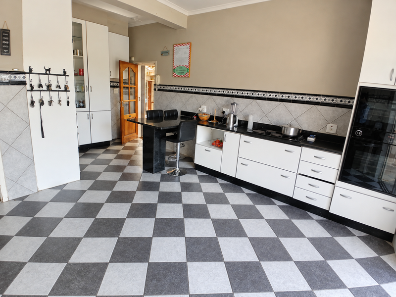 A functional kitchen featuring white cabinetry, black granite countertops, integrated oven, and a distinctive checkered tile floor.