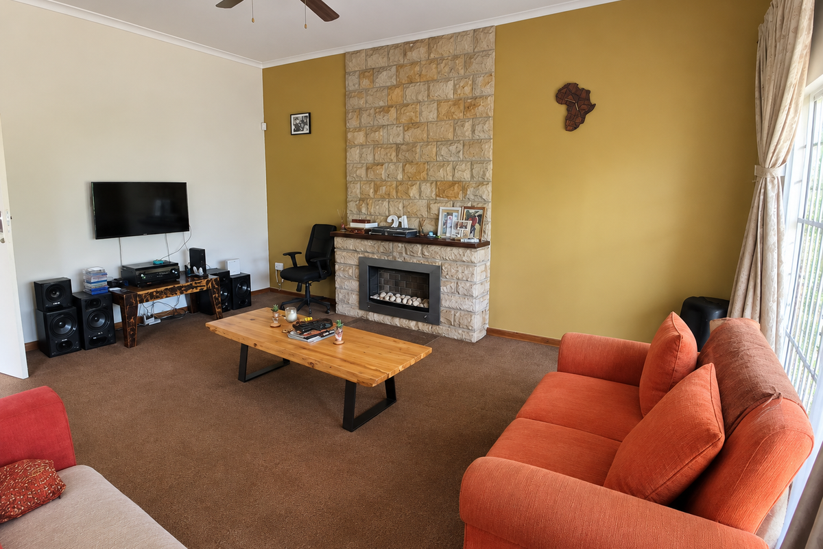 Spacious living room featuring a prominent stone-clad fireplace and ceiling fan, offering a warm and comfortable atmosphere.