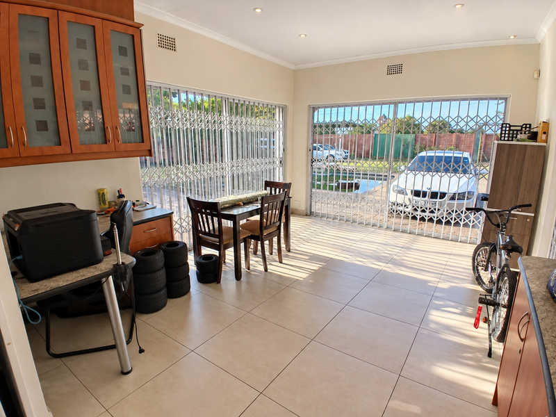 Open plan living area featuring tiled floors, recessed lighting, and large sliding glass doors with security gates leading to the exterior.