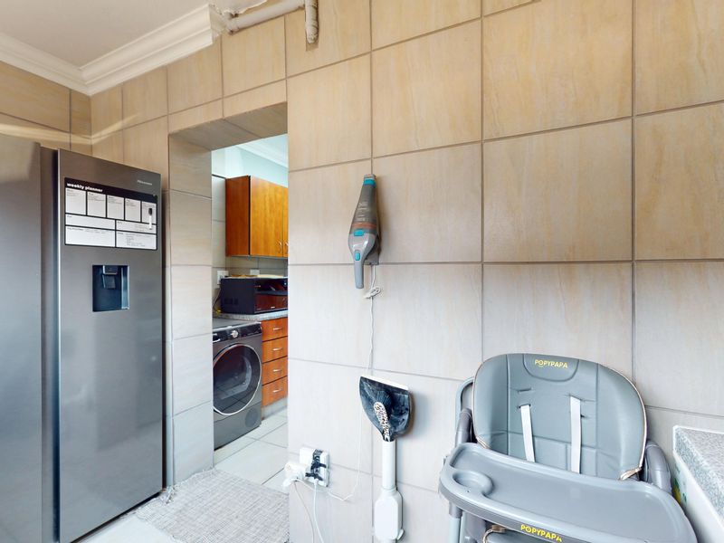 A functional scullery area featuring full-height wall tiling, built-in cabinetry, and a seamless transition to the adjacent laundry space.