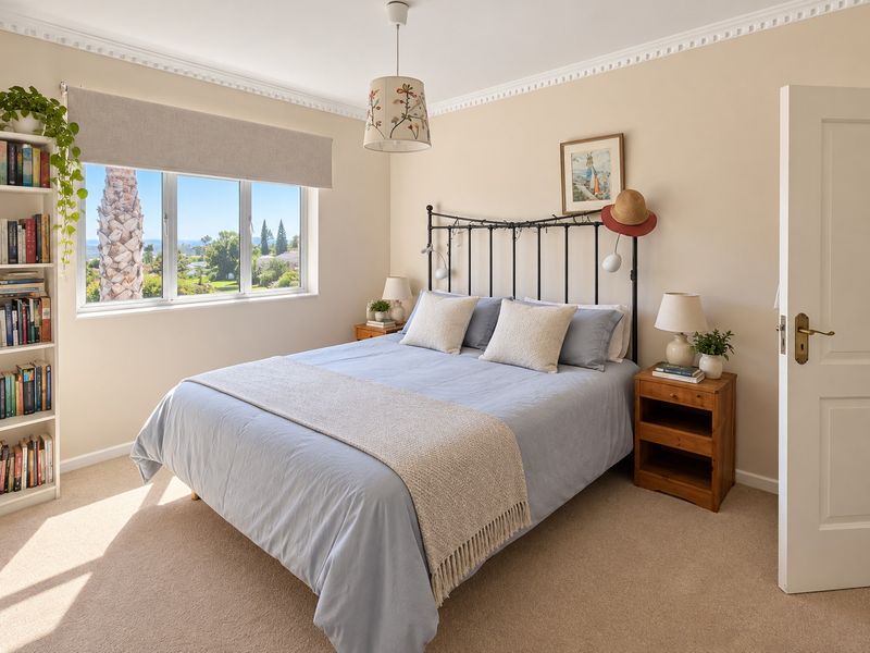 A well-maintained bedroom featuring neutral walls, crown molding, carpet flooring, and a large window with scenic views.