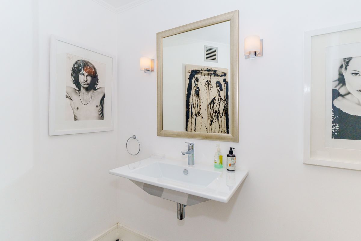A clean and modern powder room featuring a wall-mounted basin, chrome fixtures, and elegant wall-mounted lighting.