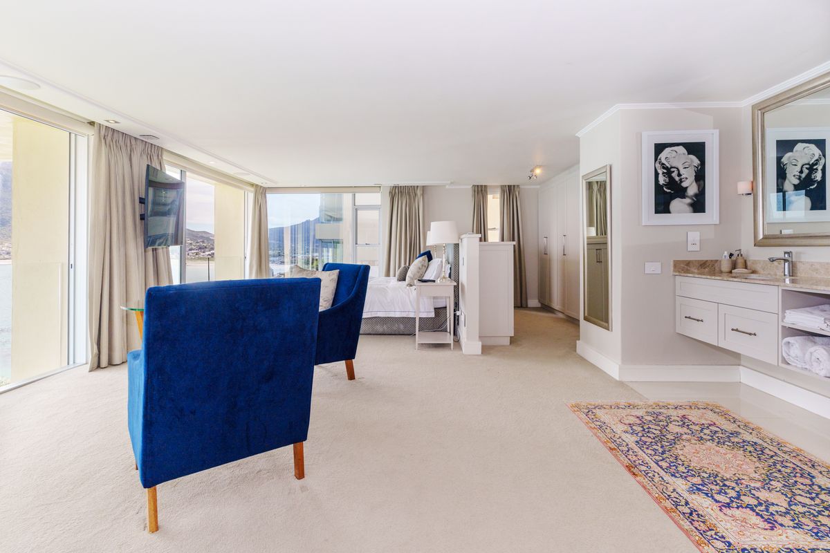 Spacious bedroom suite featuring a built-in vanity area, ample cupboard storage, and large sliding glass doors opening to a scenic balcony view.