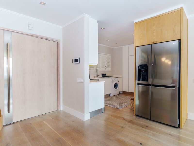 A functional scullery area featuring built-in cabinetry, timber flooring, recessed lighting, and integrated laundry facilities, providing a clean and organized utility space.