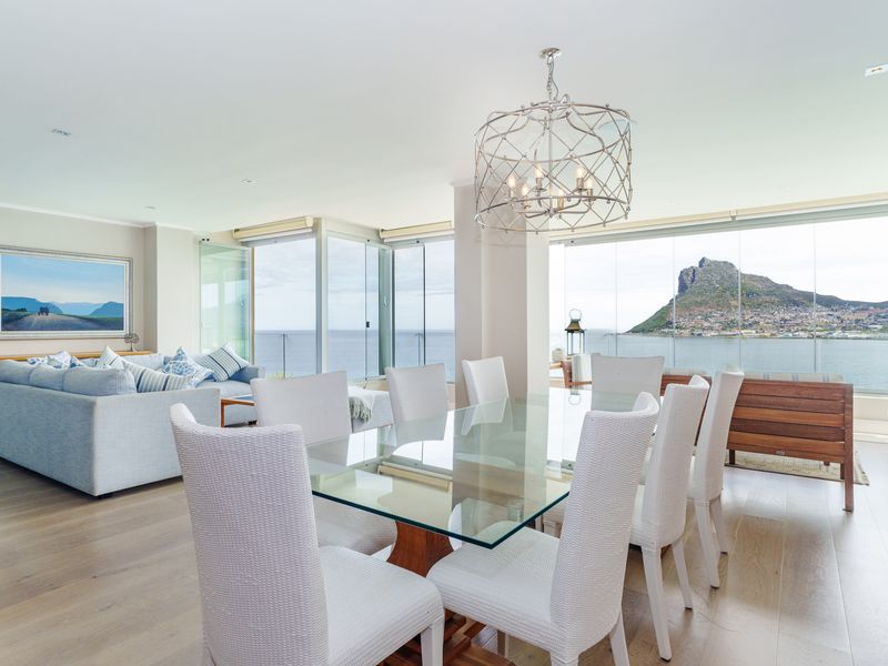 Spacious open-plan living and dining area featuring hardwood floors, recessed lighting, and expansive glass doors offering panoramic ocean and mountain views.