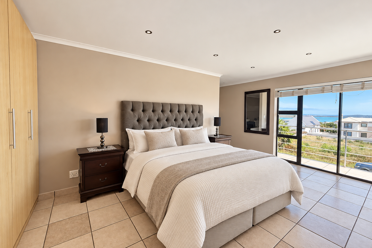 Spacious bedroom featuring built-in cupboards, tiled flooring, recessed lighting, and a large sliding glass door providing access to a balcony with scenic views.