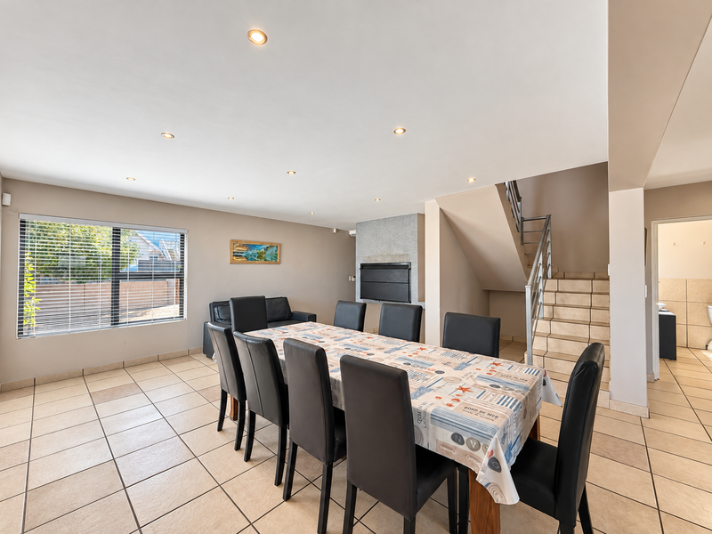 Spacious open-plan living and dining area featuring tiled flooring, a built-in fireplace, recessed lighting, and a staircase leading to the upper level.