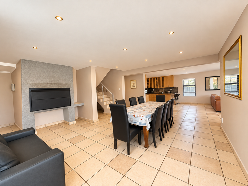 Spacious open-plan living and dining area featuring a built-in fireplace, tiled flooring, recessed lighting, and a functional kitchen with ample cabinetry.