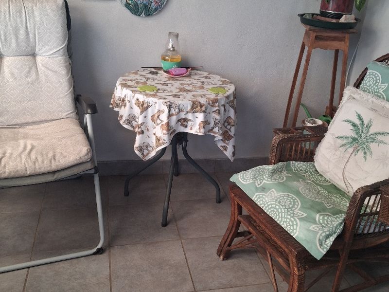 A covered patio area featuring neutral tiled flooring, providing a functional outdoor space for relaxation.