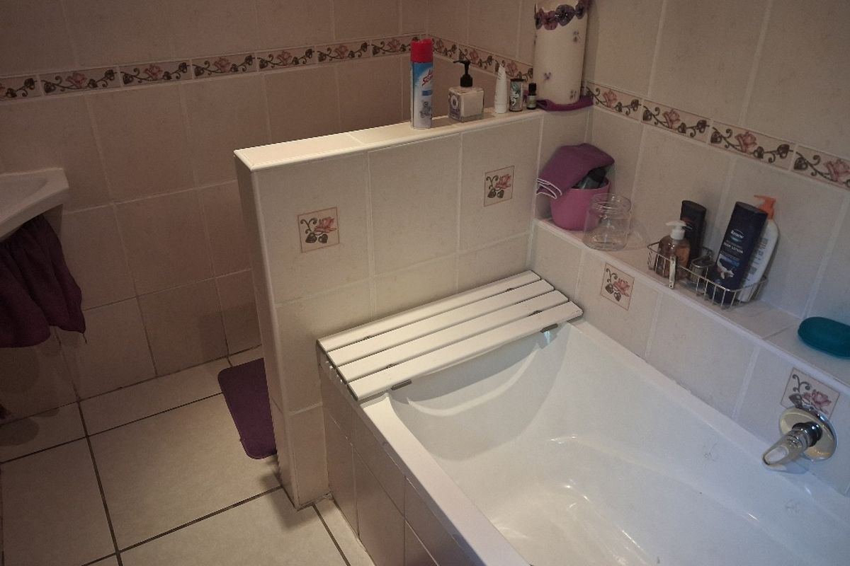 A functional bathroom featuring a built-in bathtub with tiled surround and wall finishes, offering a practical layout for daily use.