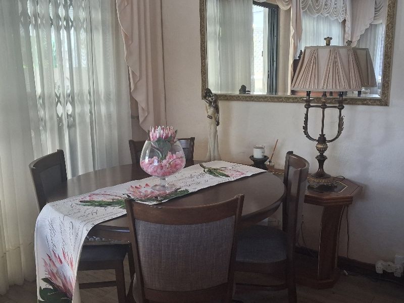 A dining room area featuring laminate flooring and a large wall-mounted mirror, providing a functional space for meals.