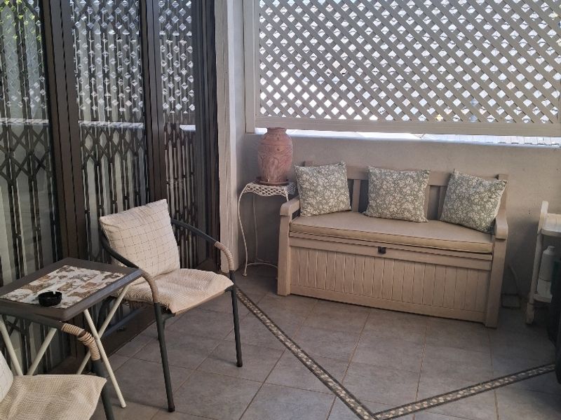A covered patio area featuring tiled flooring, a decorative lattice privacy screen, and sliding glass door access to the interior.