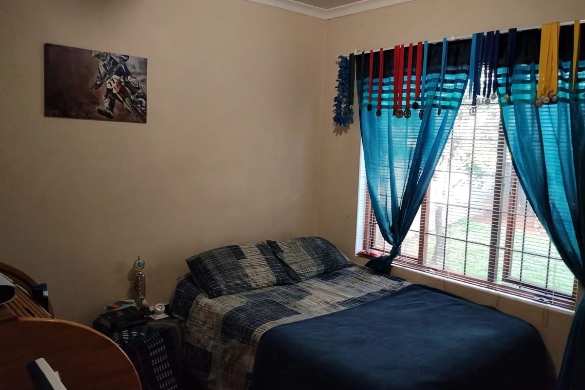 A standard bedroom featuring a window with security bars and neutral wall finishes.