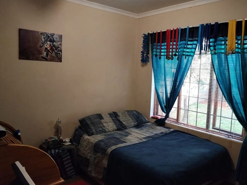 A standard bedroom featuring a window with security bars and neutral wall finishes.