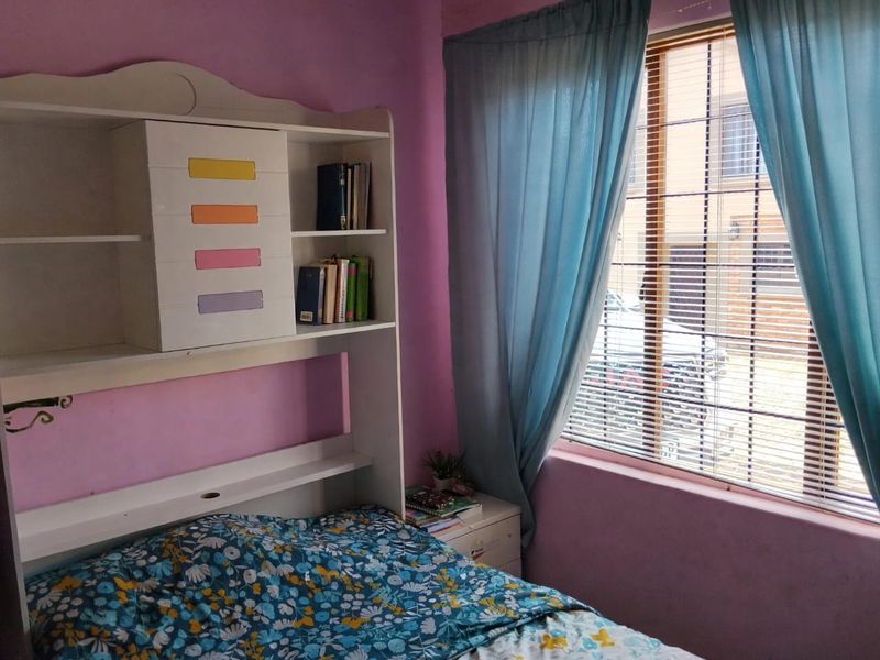 A bedroom featuring a window with venetian blinds and purple wall paint, requiring cosmetic updates to improve the overall aesthetic.
