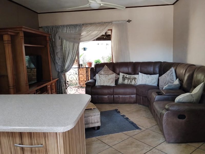 Open plan living area featuring tiled flooring, a central kitchen island, and access to a balcony with wrought iron detailing.