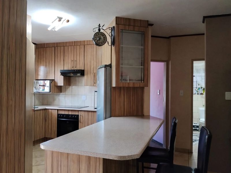 Functional kitchen featuring wood-look laminate cabinetry, a built-in oven with hob, extractor fan, and a convenient breakfast bar island.