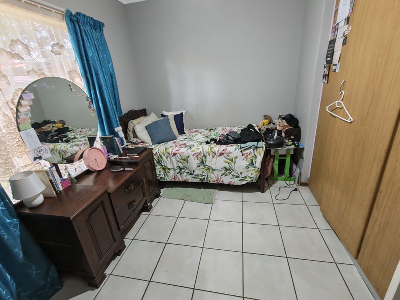 A functional bedroom featuring tiled flooring and a built-in wardrobe, offering a practical space with neutral wall finishes.