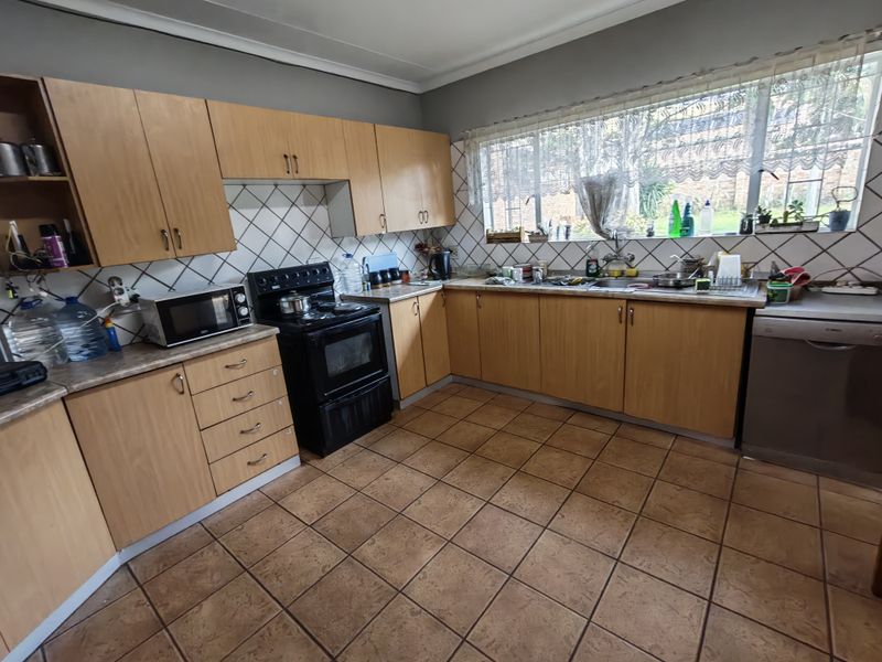 A functional kitchen featuring wood-look laminate cabinetry, a diamond-patterned tile backsplash, ceramic floor tiles, and a built-in oven with hob.