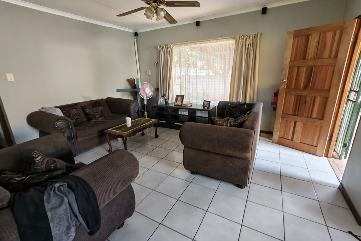 A living room featuring tiled flooring, a ceiling fan, and a solid wooden entrance door.