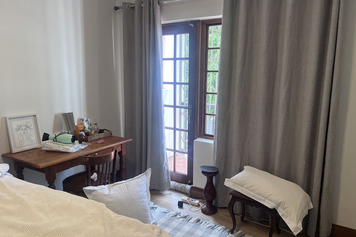 A bedroom featuring timber-framed windows and a glass door providing access to the exterior, with neutral walls and wooden flooring.