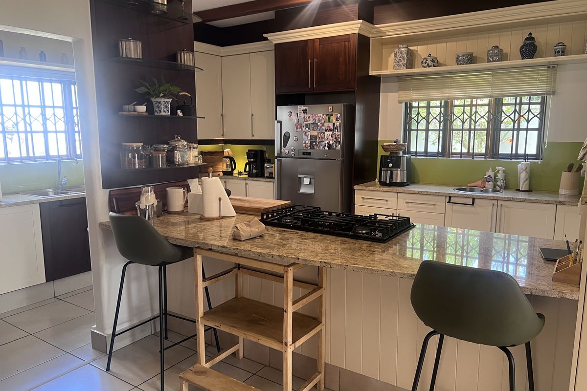 A functional kitchen featuring granite countertops, a gas hob, ample built-in cabinetry, and a secondary prep area with a sink.