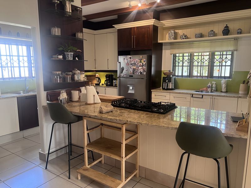 A functional kitchen featuring granite countertops, a gas hob, ample built-in cabinetry, and a secondary prep area with a sink.