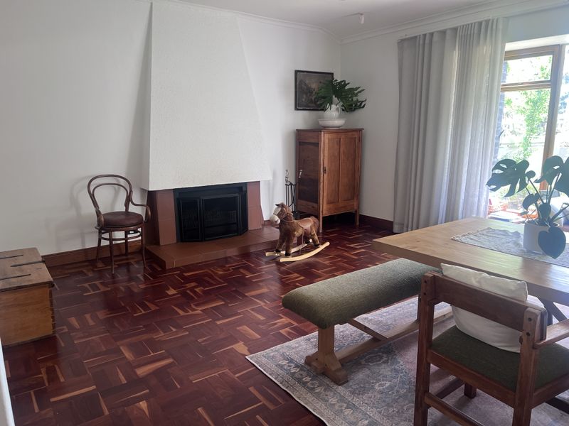 A well-maintained living room featuring rich parquet flooring, a prominent fireplace with a textured surround, and large sliding doors providing natural light.