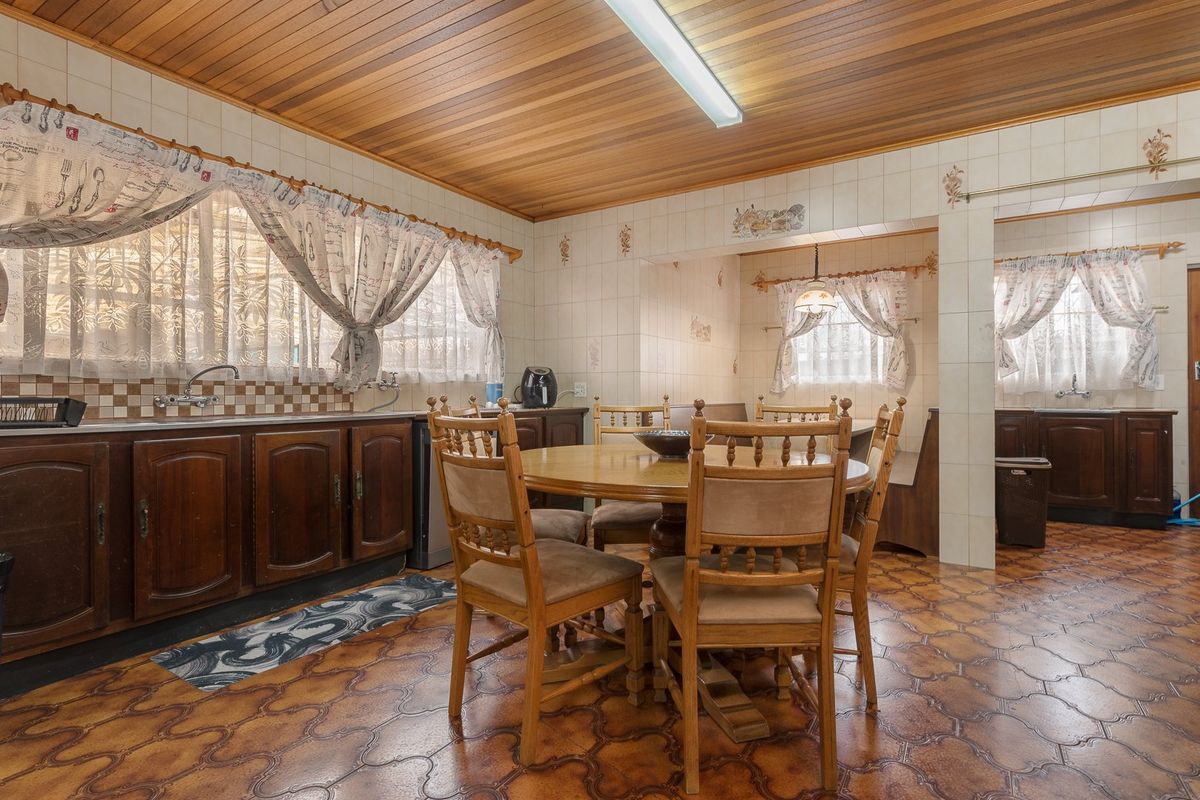 A dated kitchen featuring timber cabinetry, tiled walls, and a wood-paneled ceiling, offering significant potential for a modern renovation.