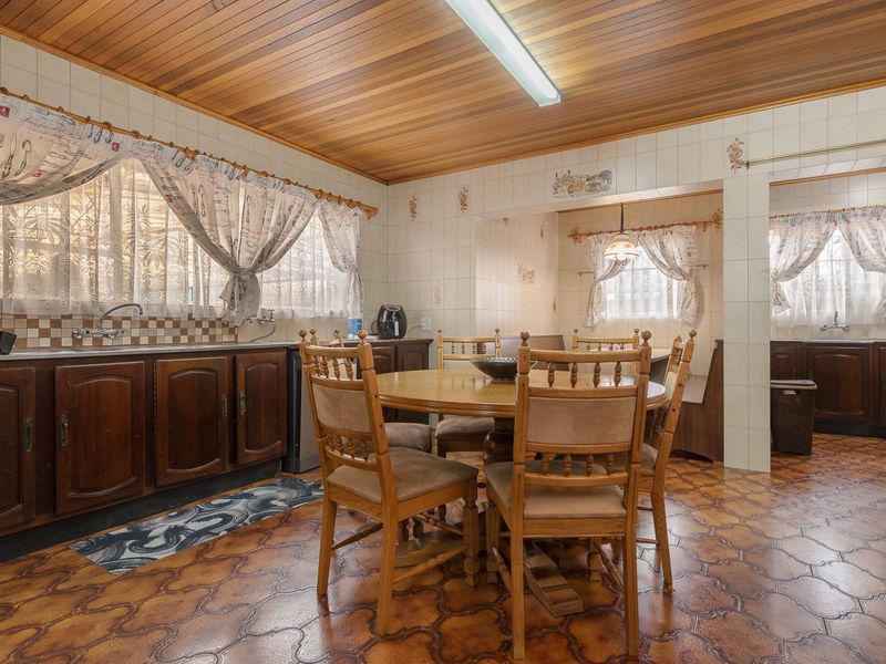 A dated kitchen featuring timber cabinetry, tiled walls, and a wood-paneled ceiling, offering significant potential for a modern renovation.