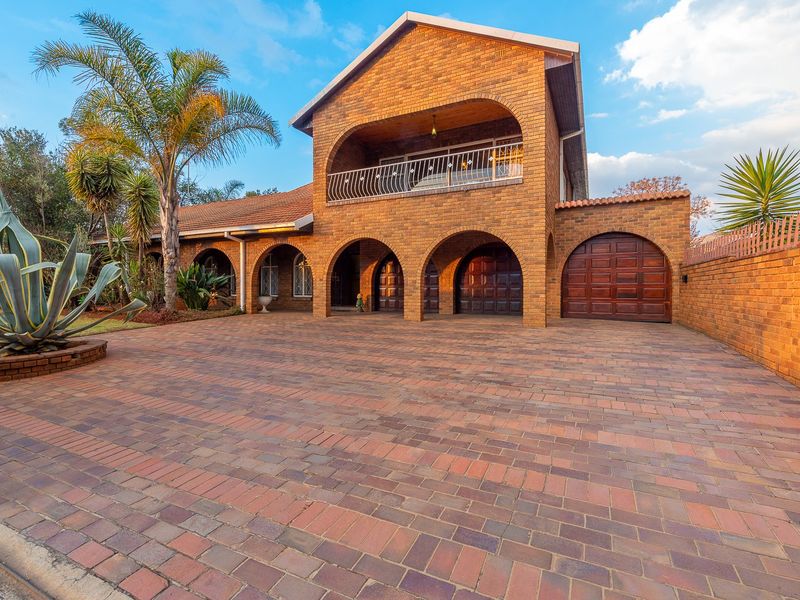 A well-maintained double-story brick residence featuring an arched front facade, a paved driveway, and an integrated garage.