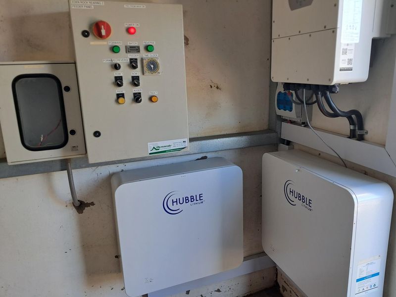 Utility area featuring a dedicated electrical control panel, inverter, and dual lithium battery storage system for power management.