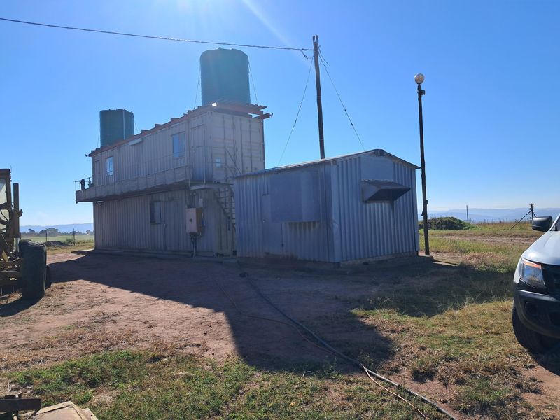 Exterior view of a utility structure featuring corrugated metal construction and elevated water storage tanks on a rural small holding.
