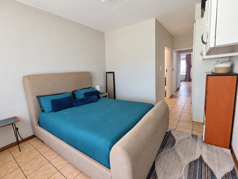 A bedroom featuring tiled flooring and built-in cabinetry, with a view leading into a hallway and adjacent room.