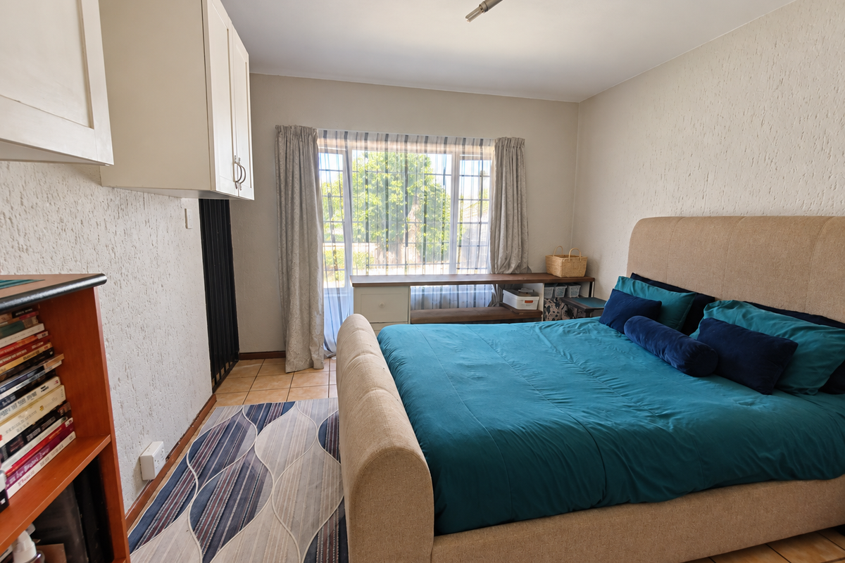 A bedroom featuring textured walls, tiled flooring, and built-in cabinetry, offering a functional space with natural light from the window.