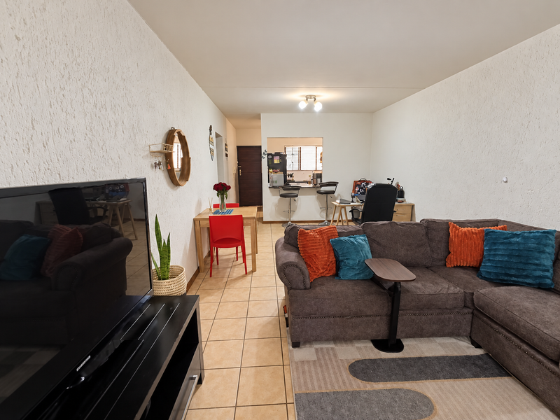 Open-plan living and dining area featuring tiled flooring, textured walls, and a convenient breakfast bar connecting to the kitchen space.