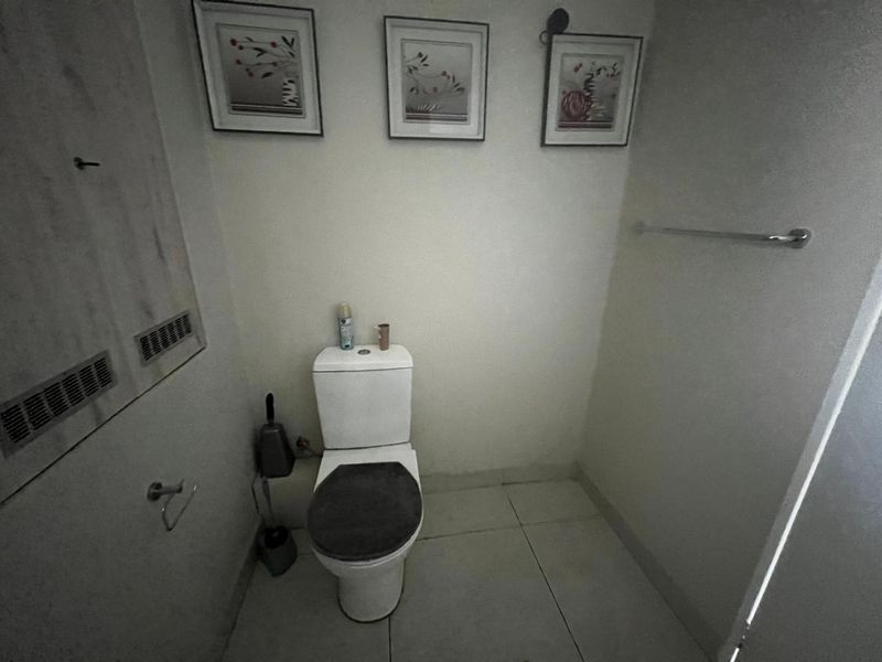 A functional bathroom featuring a standard toilet, tiled flooring, and a wall-mounted towel rail.