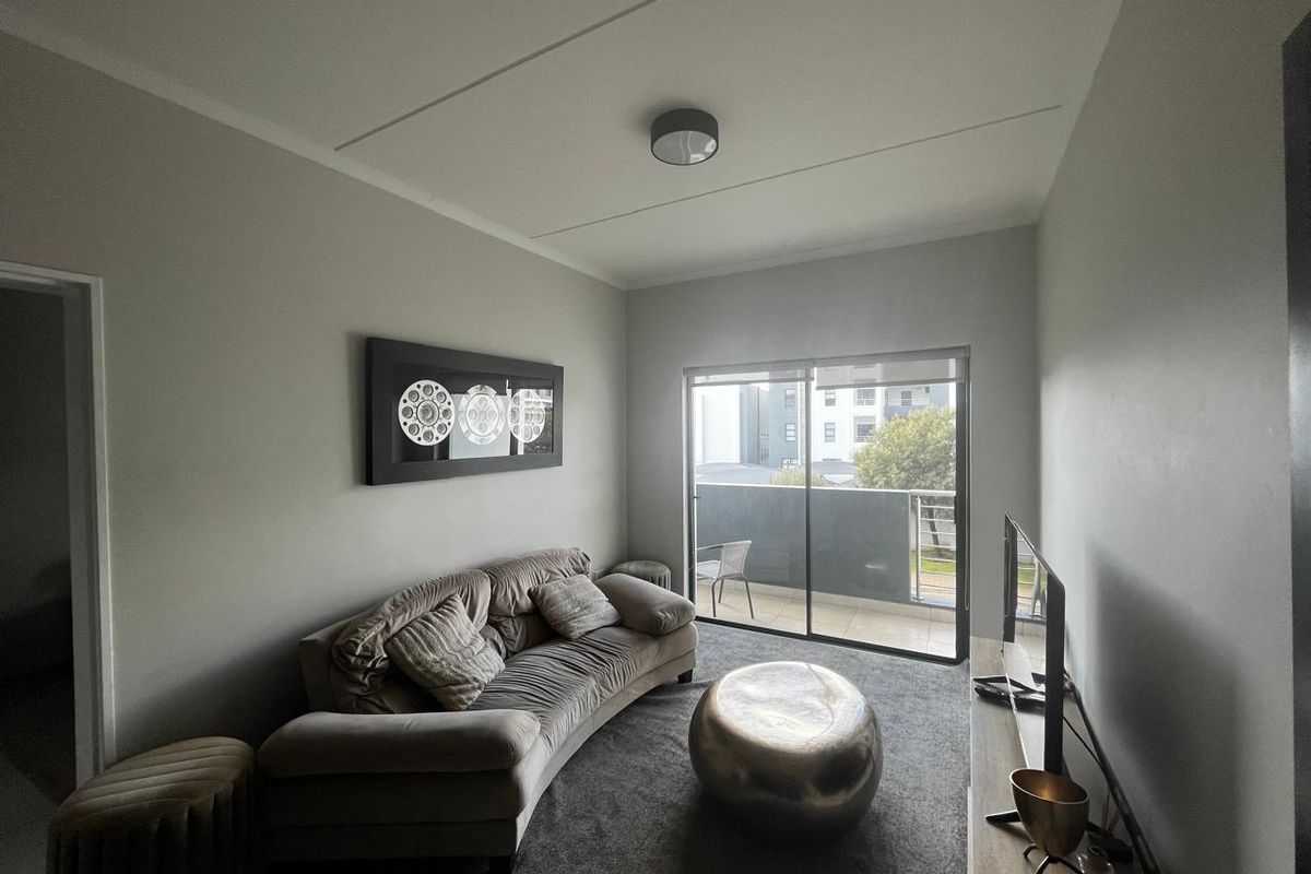 A comfortable living room featuring carpeted flooring and a sliding glass door that provides access to a private balcony.