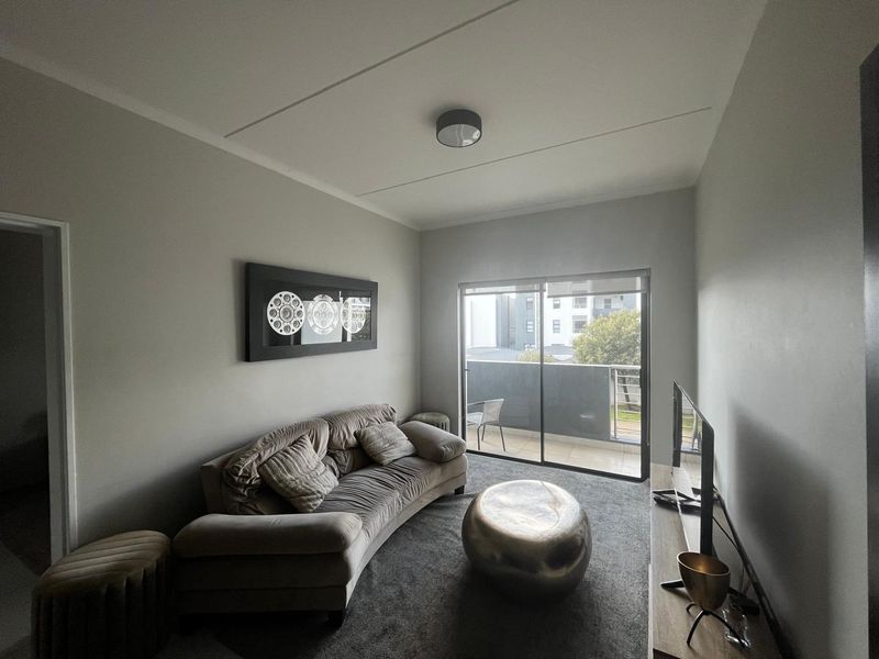 A comfortable living room featuring carpeted flooring and a sliding glass door that provides access to a private balcony.