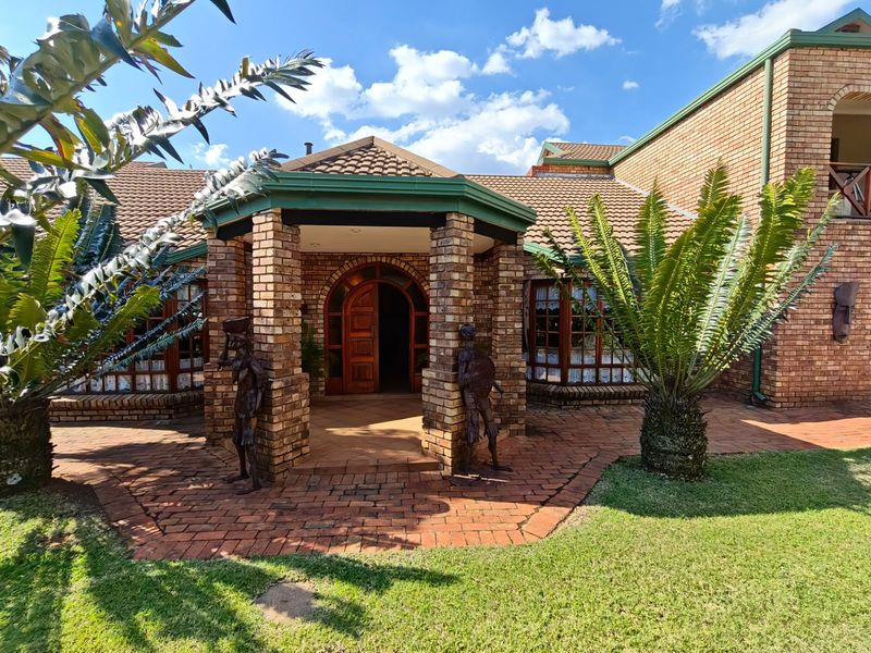 A well-maintained face brick home featuring a covered entrance porch, arched timber front door, and paved walkway set within a landscaped garden.