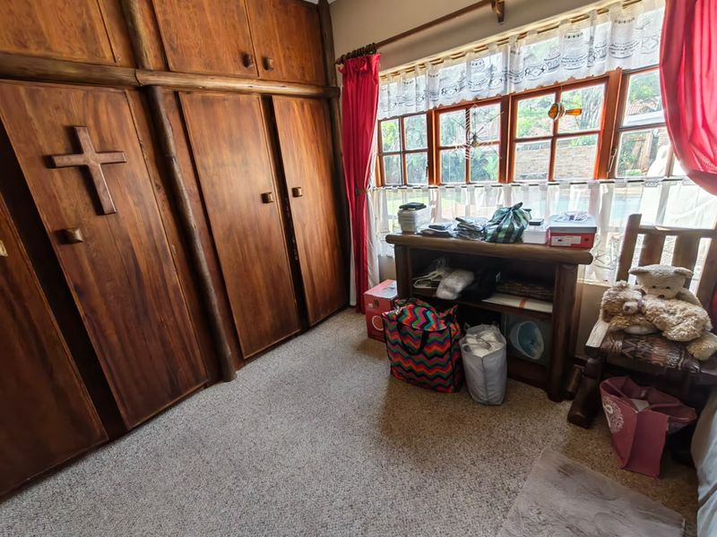 A bedroom featuring extensive built-in wooden cabinetry and timber-framed windows, providing ample storage and natural light.