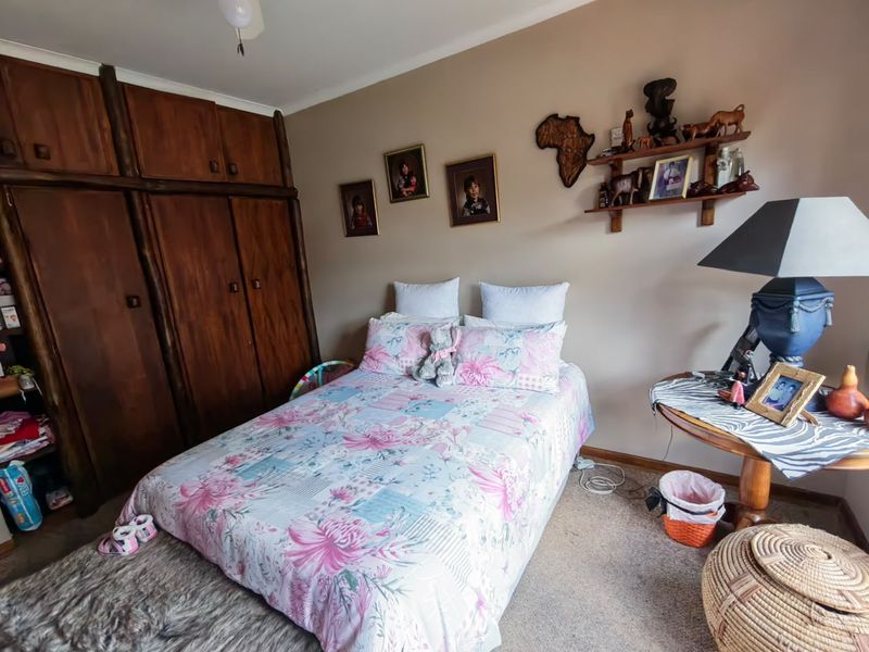 A bedroom featuring built-in wooden cupboards and a ceiling fan, offering a functional space with traditional cabinetry.