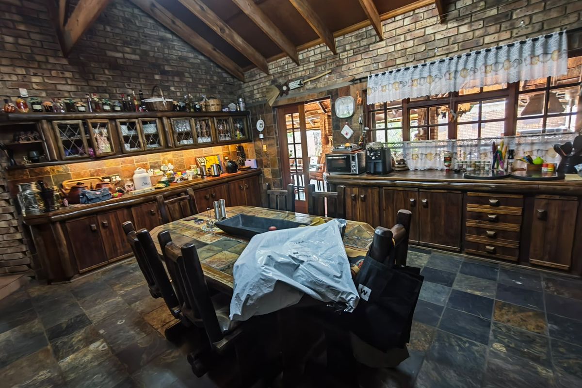 Rustic kitchen featuring exposed timber beams, brick walls, slate flooring, and extensive custom timber cabinetry with a warm, traditional aesthetic.