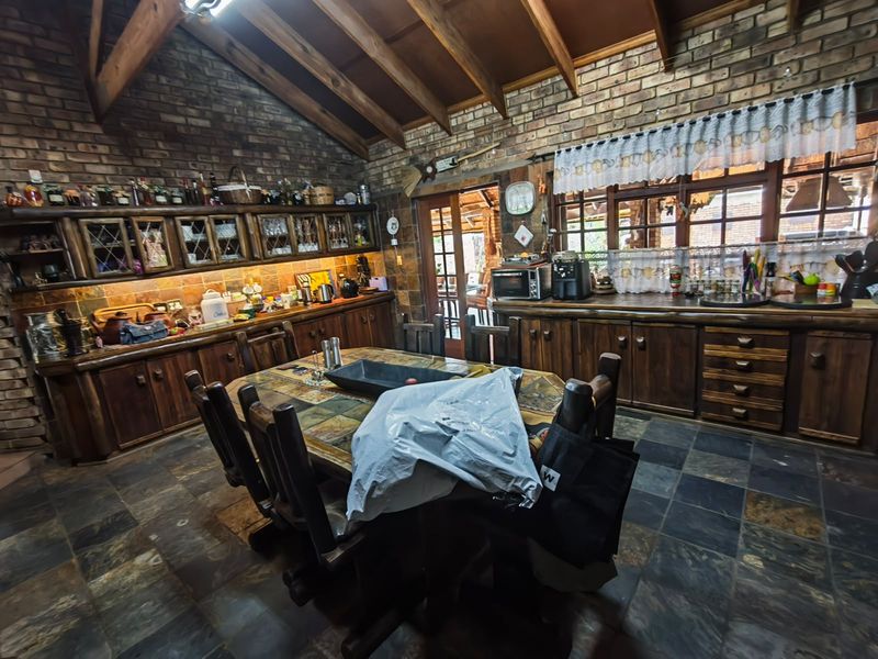 Rustic kitchen featuring exposed timber beams, brick walls, slate flooring, and extensive custom timber cabinetry with a warm, traditional aesthetic.