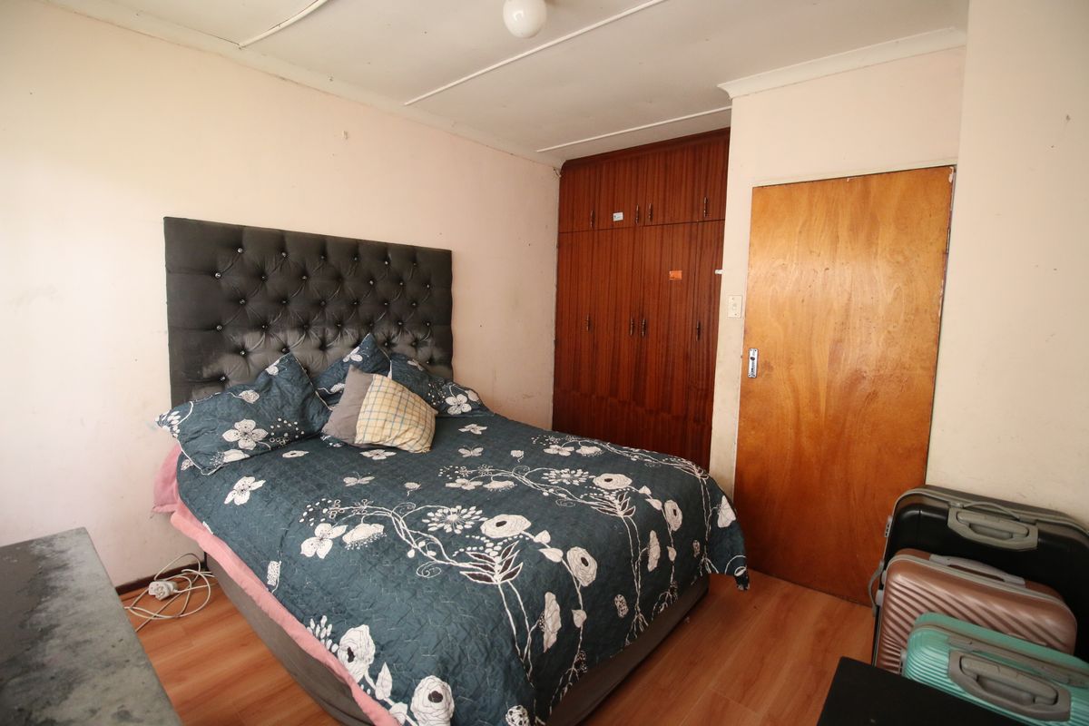 A bedroom featuring built-in wooden wardrobes, laminate flooring, and a coved ceiling. The room requires cosmetic updates to improve its overall condition.