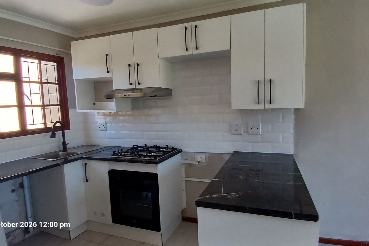 A functional kitchen featuring white cabinetry, dark stone countertops, a gas hob, and a subway tile backsplash, currently awaiting final finishing touches.