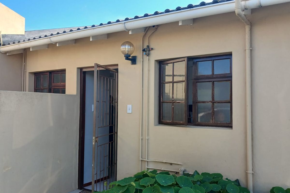 Rear exterior view of the townhouse featuring a security gate, timber-framed windows, and functional guttering system.