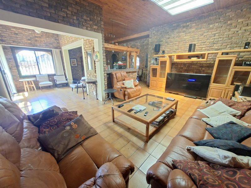 Spacious open-plan living area featuring exposed brick walls, a timber ceiling with a skylight, and durable tiled flooring throughout.