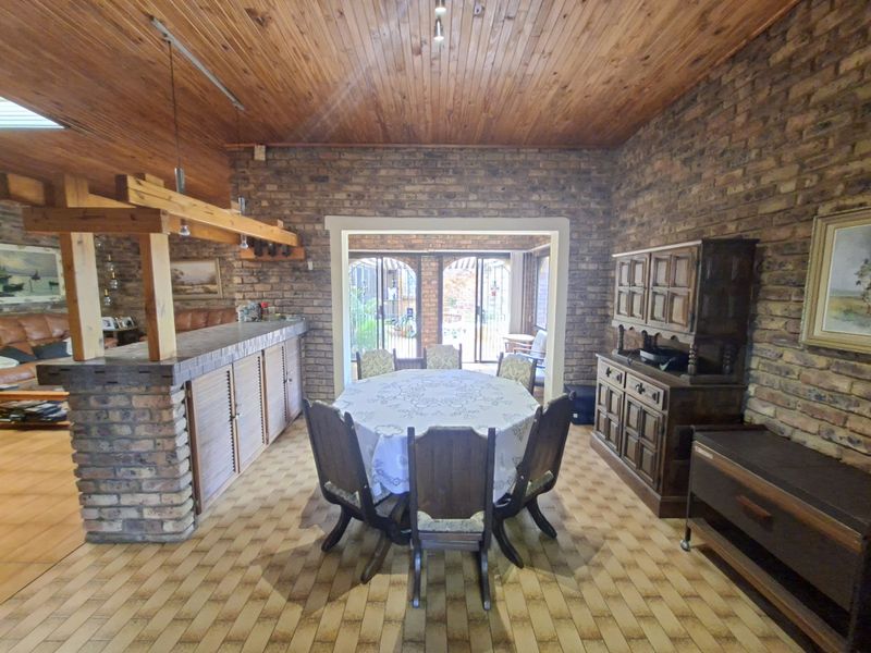 Spacious dining area featuring exposed brick walls, a timber ceiling, and a built-in brick bar, with direct access to an outdoor patio area.